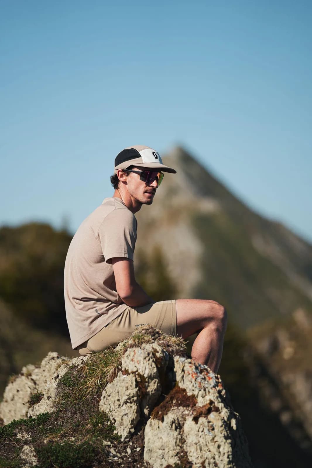 Thomas Derême assis sur un rocher face aux montagnes